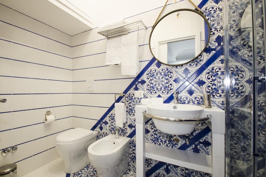 A bathroom with a bidet, toilet, and a sink with a mirror above it.