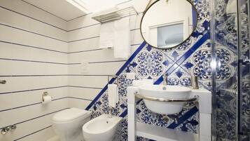 A bathroom with a bidet, toilet, and a sink with a mirror above it.