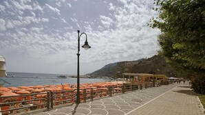 Un paseo marítimo con sombrillas naranjas y un sendero pavimentado.