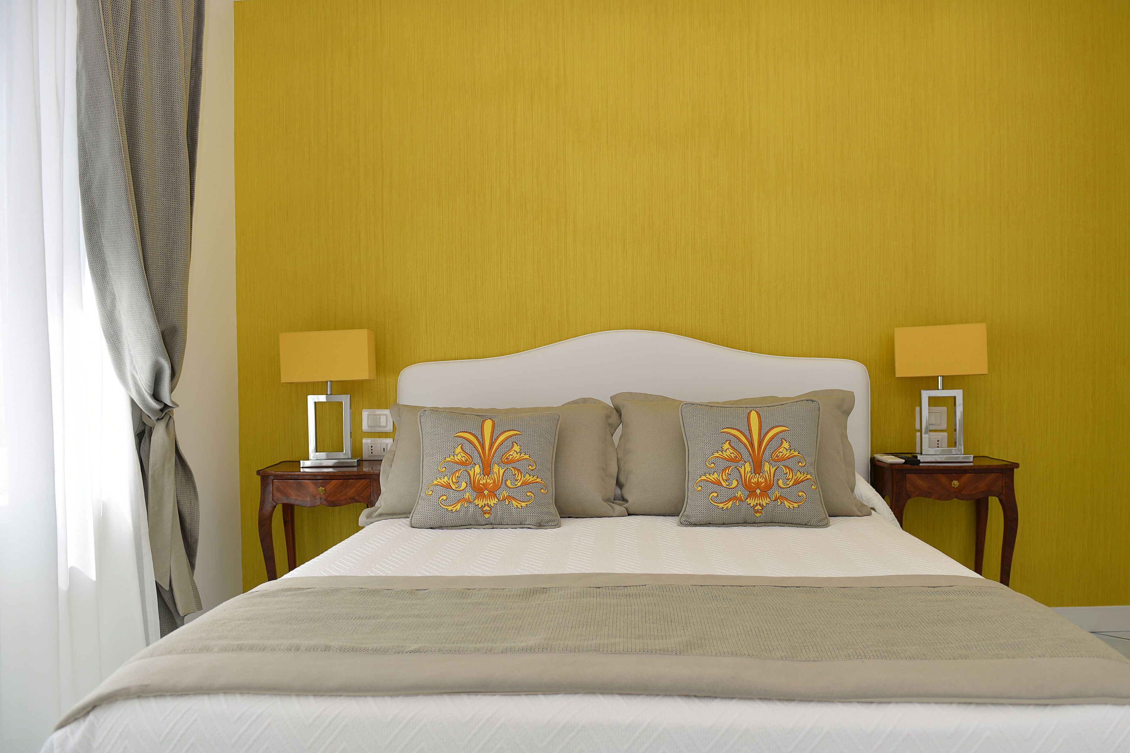 A neatly made bed with a white headboard, two bedside tables with lamps, and decorative pillows.