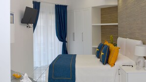 Una habitación de hotel moderna con una cama bien hecha, un televisor de pantalla plana en la pared y una mesita de noche con una lámpara.
