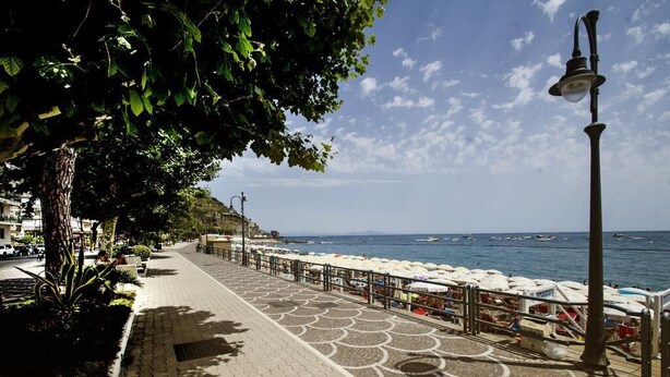 Un paseo marítimo con un sendero estampado, sombrillas de playa y vistas al mar.