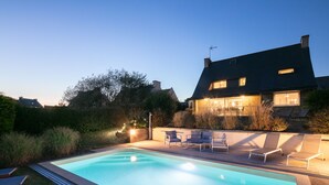 Une piscine avec des chaises longues et un espace patio.