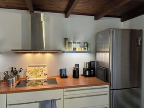 Une cuisine moderne dotée d’un réfrigérateur en acier inoxydable, d’un four encastré et d’un plafond en bois.