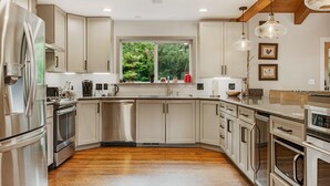 A modern kitchen with stainless steel appliances, white cabinetry, and a wooden floor. - Vail mountain house! 5 bedrooms plus loft.  Hot tub! (Vail)