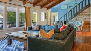A spacious living room with a high ceiling, a wooden staircase, and a view of the outdoors. - Vail mountain house! 5 bedrooms plus loft.  Hot tub! (Vail)