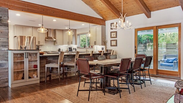 A spacious kitchen with wooden beams, a large island, and a dining area with six chairs. - Vail mountain house! 5 bedrooms plus loft.  Hot tub! (Vail)