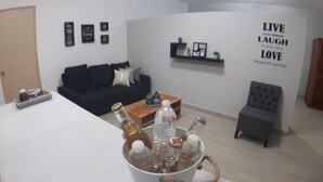A living room with a white coffee table, a black sofa, a grey armchair, and a wall with motivational quotes.