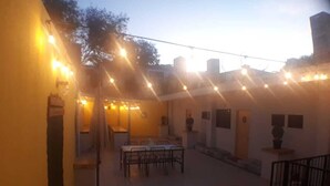 An outdoor patio area with string lights, wooden tables, and chairs.