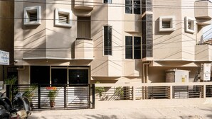 Un immeuble à plusieurs étages, doté d’une façade beige, de nombreuses fenêtres et d’une entrée fermée par un portail.