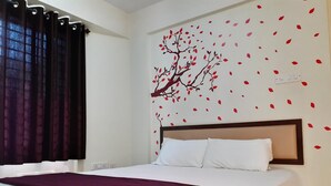 Une chambre d’hôtel avec un lit, une tête de lit et une décoration murale représentant un arbre avec des feuilles.