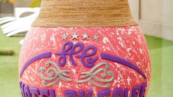 A red vase with "HOTEL DU GOLF" written on it, placed on a stand.