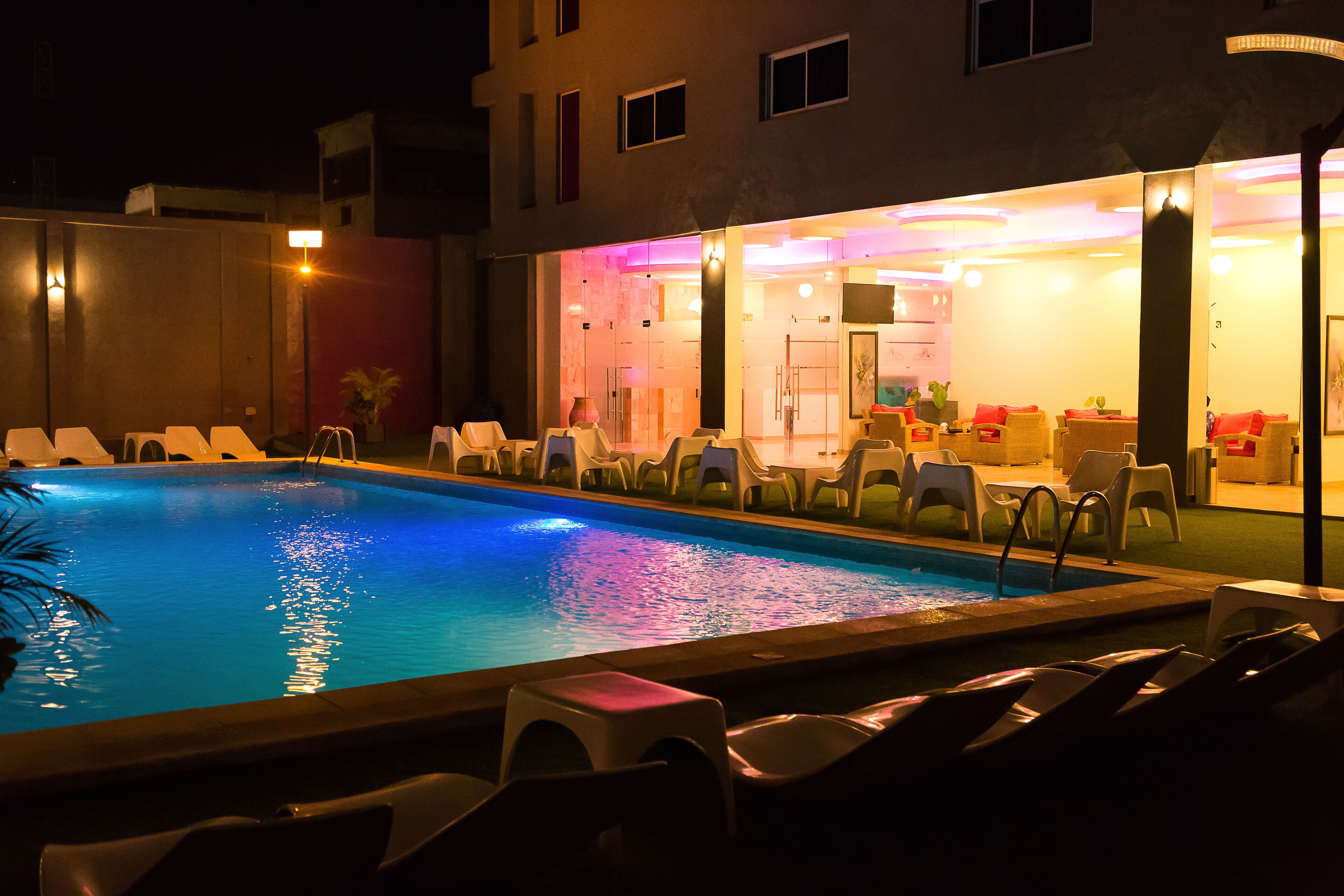 Une piscine dotée de chaises longues et d’un espace intérieur bien éclairé.