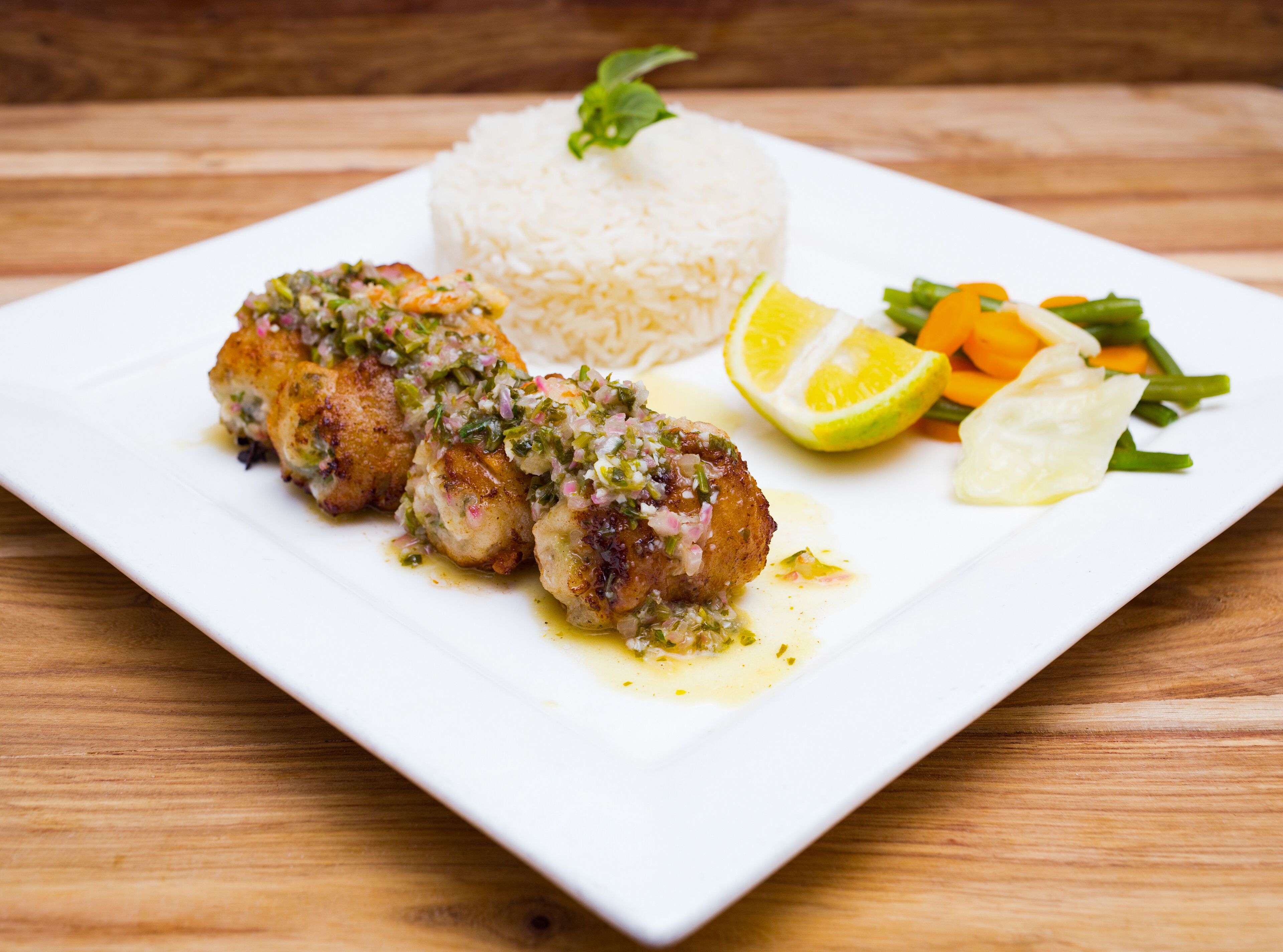 Un plato con dos trozos de pollo empanizado, una porción de arroz blanco y una guarnición de vegetales mixtos.