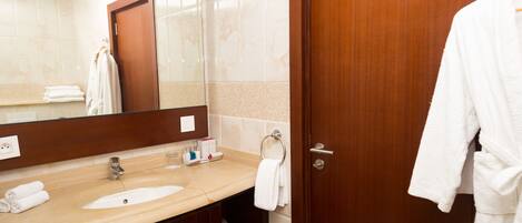 A hotel bathroom with a wooden door, a large mirror, a sink, and a towel rack.