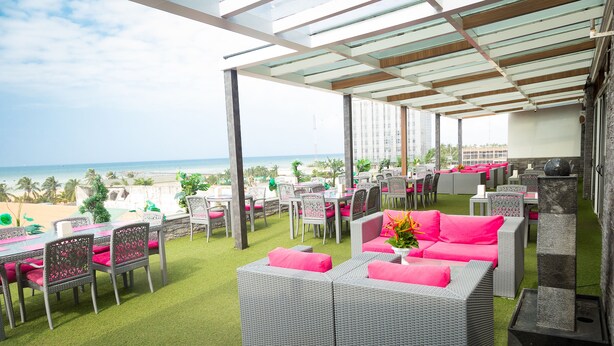 An outdoor patio with wicker furniture and a view of the beach. - Hôtel du Golfe (Lomé)