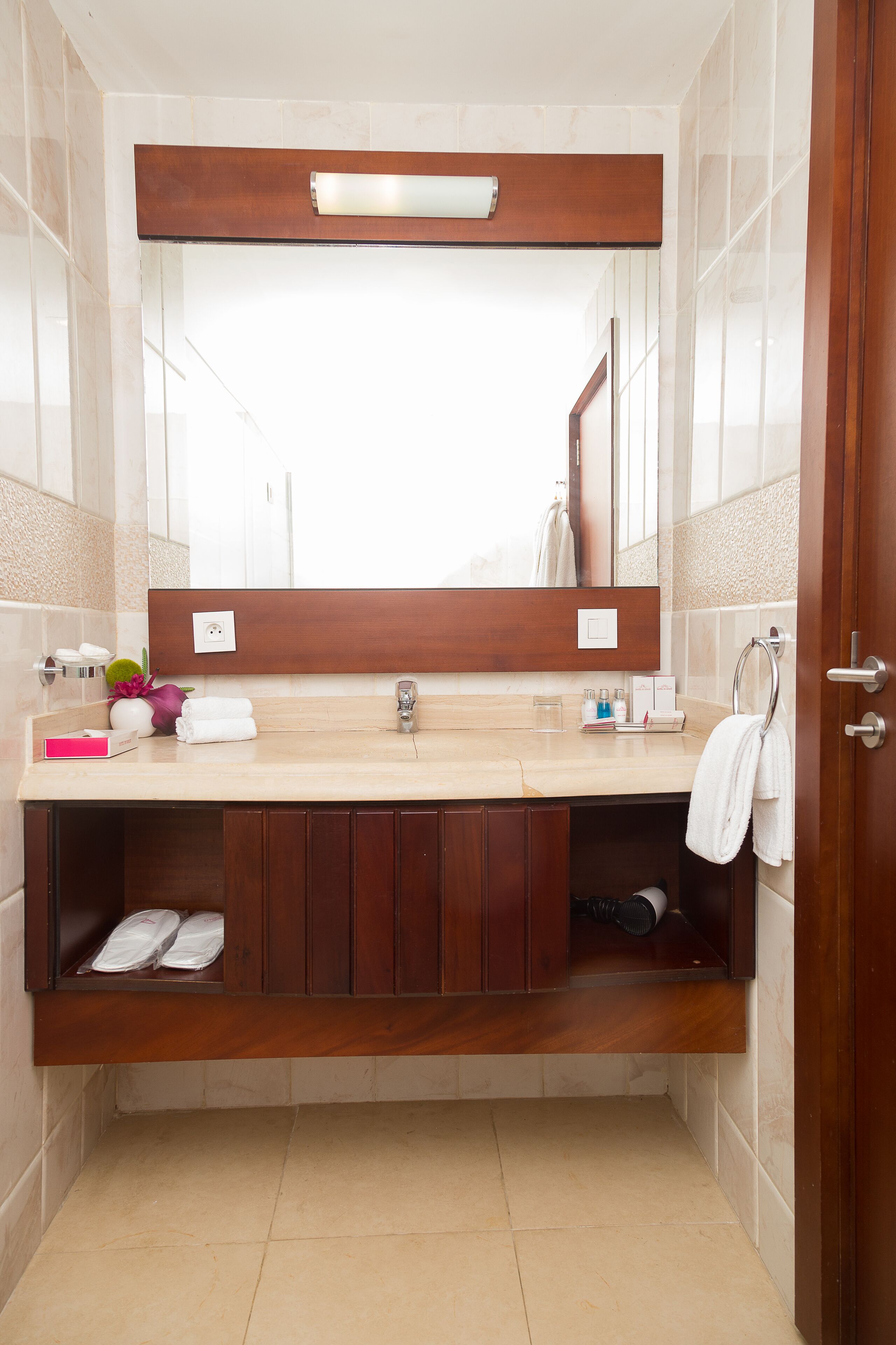 A bathroom with a wooden vanity, a mirror, and a towel rack.
