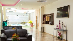 A modern hotel lobby with leather sofas, a console table with decorative items, and a large window offering a view of the pool area. - Hôtel du Golfe (Lomé)