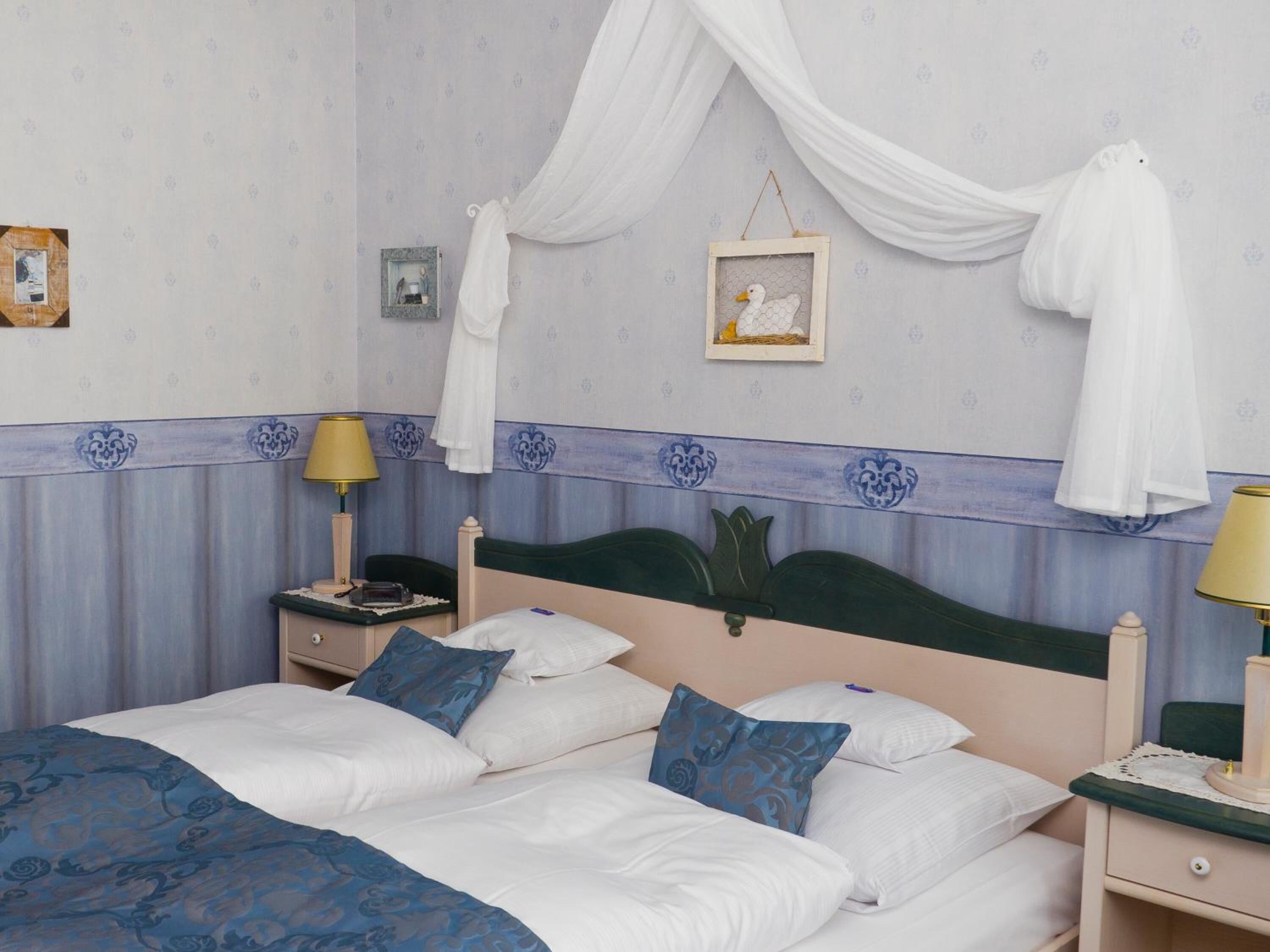 Una habitación de hotel con una cama, dos mesitas de noche, una lámpara, un cuadro y una cortina.