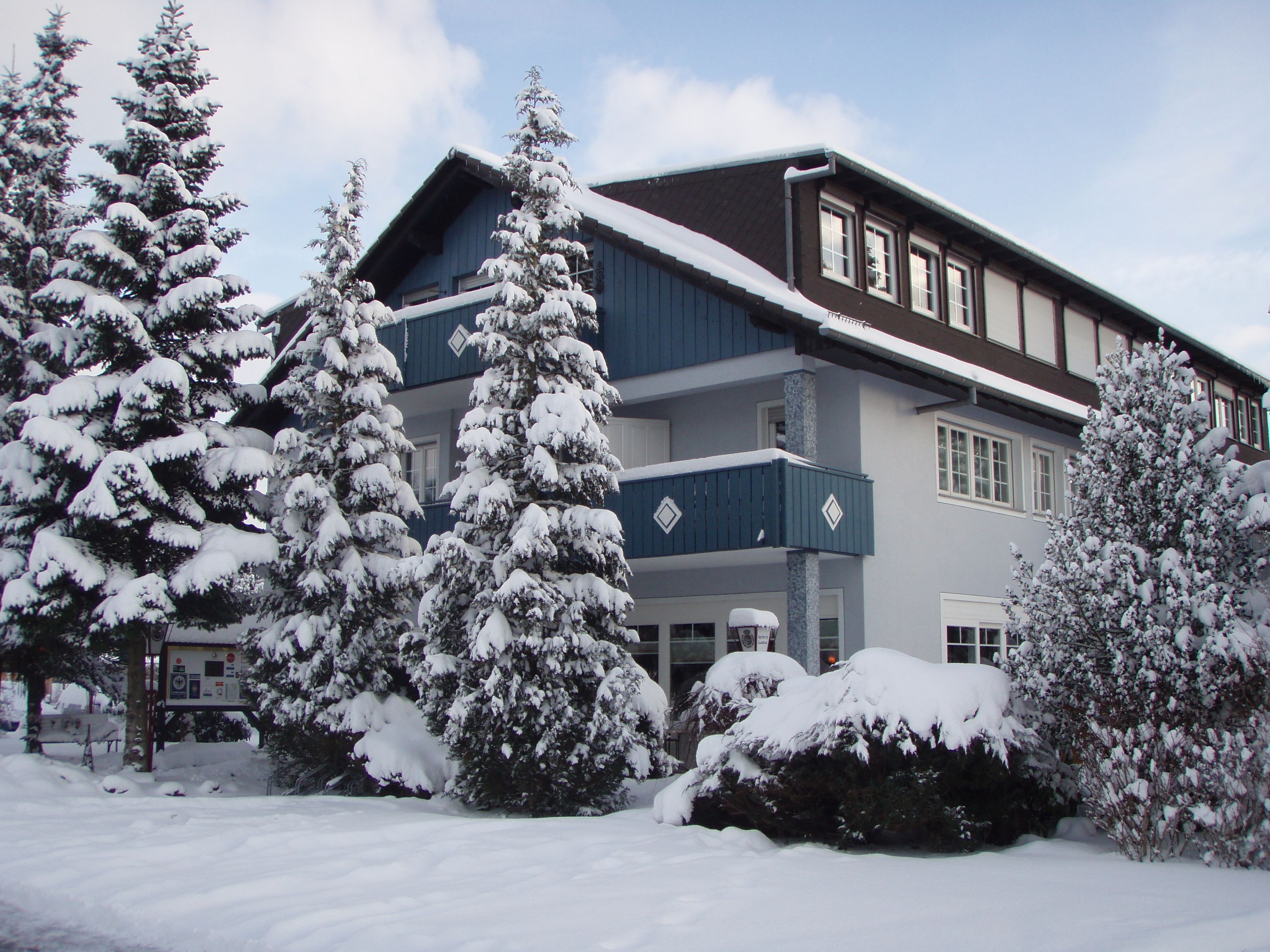 A two-story building with a snow-covered roof and surrounding trees.