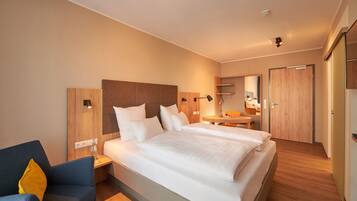 A hotel room with a large bed, bedside tables, a chair, a desk, and a mirror.