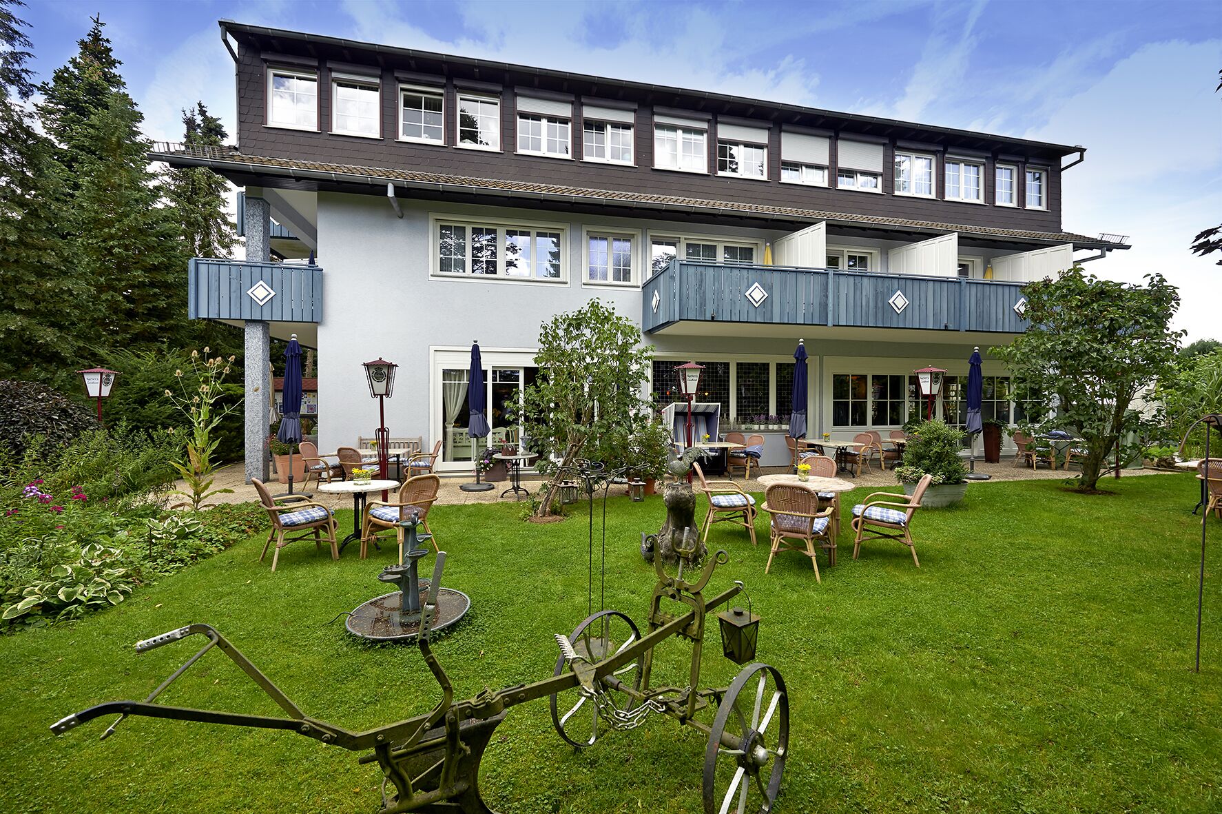A two-story building with a patio area featuring outdoor furniture and a garden.
