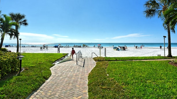 A paved pathway leading to a beach with palm trees and a clear blue sky. - Spectacular Beach View! Right on Beach! Amazing views from all rooms! Sleeps 6 (Siesta Key)