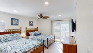 A bedroom with two beds, a ceiling fan, a TV mounted on the wall, and a balcony with a view.