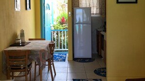 Une cuisine compacte équipée d’un réfrigérateur, d’un coin repas avec une table et des chaises, et d’un ventilateur de plafond.
