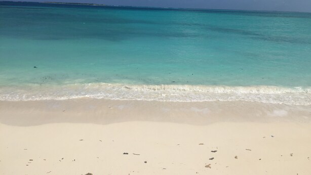 Une plage à l’eau turquoise et au sable blanc.