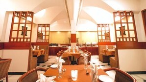 Un restaurante con mesas largas, separadores de madera y un techo alto.