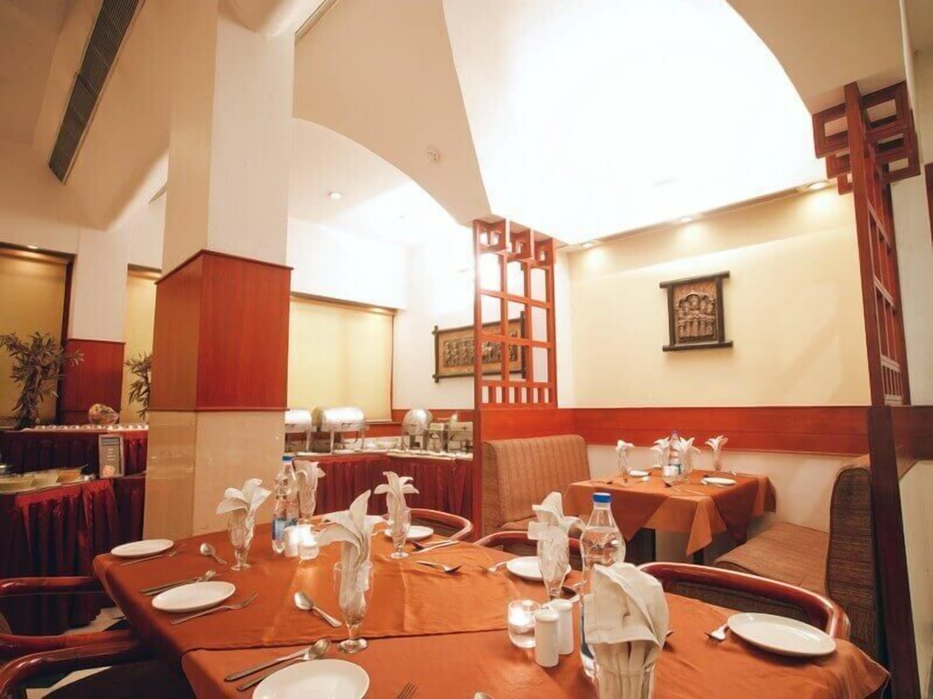 A dining area with tables set for a meal, featuring a high ceiling and wooden paneling.