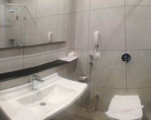 Ein Badezimmer mit einem weißen Waschbecken, einem Spiegel, einer Toilette und einer Dusche.