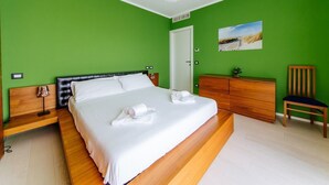 A bedroom with a large bed, a wooden dresser, a chair, and a painting on the wall. - Welc-oM Daniel's (Selvazzano Dentro)