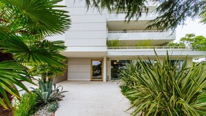 A modern building with a flat roof, a balcony on the second floor, and a paved entrance area with plants. - Welc-oM Daniel's (Selvazzano Dentro)