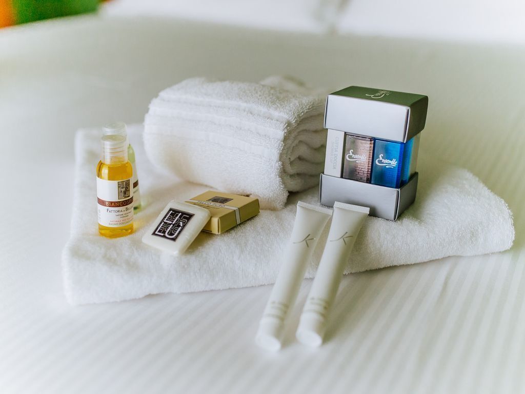 A neatly arranged bathroom with a white towel, a bottle of lotion, a bar of soap, and a tube of cream on a white surface.