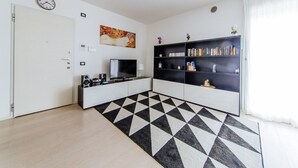 A modern living room with a black and white geometric rug, a bookshelf, a flat-screen TV, and a clock on the wall. - Welc-oM Daniel's (Selvazzano Dentro)