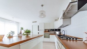 A modern kitchen with white cabinetry, a wooden countertop, and a gas stove. - Welc-oM Daniel's (Selvazzano Dentro)