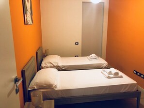 Una habitación de hotel con dos camas, un espejo y una mesita de noche con lámpara.