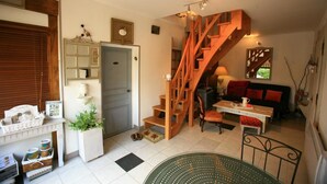 Una sala de estar acogedora con una escalera de madera, una mesa de comedor y un sofá.