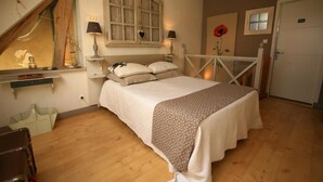 Un dormitorio con cama, ventana, lámpara, puerta y una pared con un cuadro de flores.