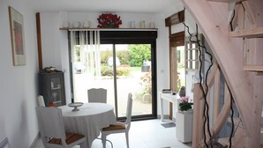 Un comedor con una mesa redonda y sillas, un armario, y vistas al exterior a través de un ventanal.