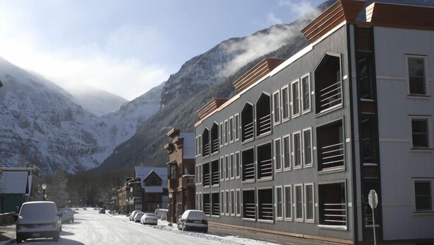 A snow-covered street with buildings, including a multi-story structure with large windows and a flat roof. - 'Best Deal in Telluride' - Walk to Gondola & lift 8!     TBL #00111 (Telluride)