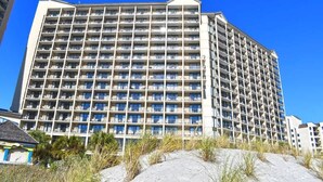 Un hotel de varios pisos con una distribución en cuadrícula de habitaciones, balcones y techo plano.