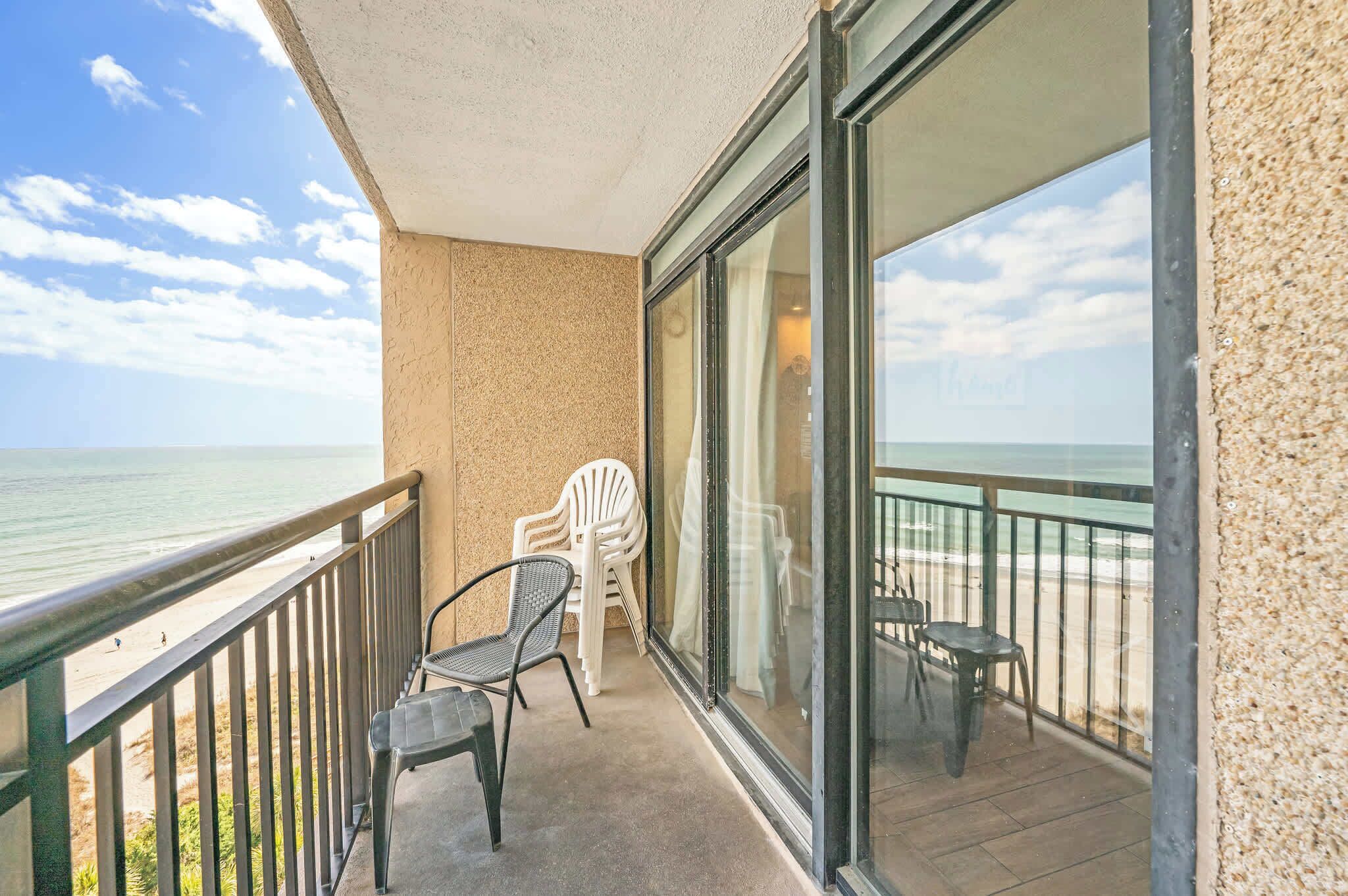 Un balcon avec vue sur la plage, une chaise et une table.