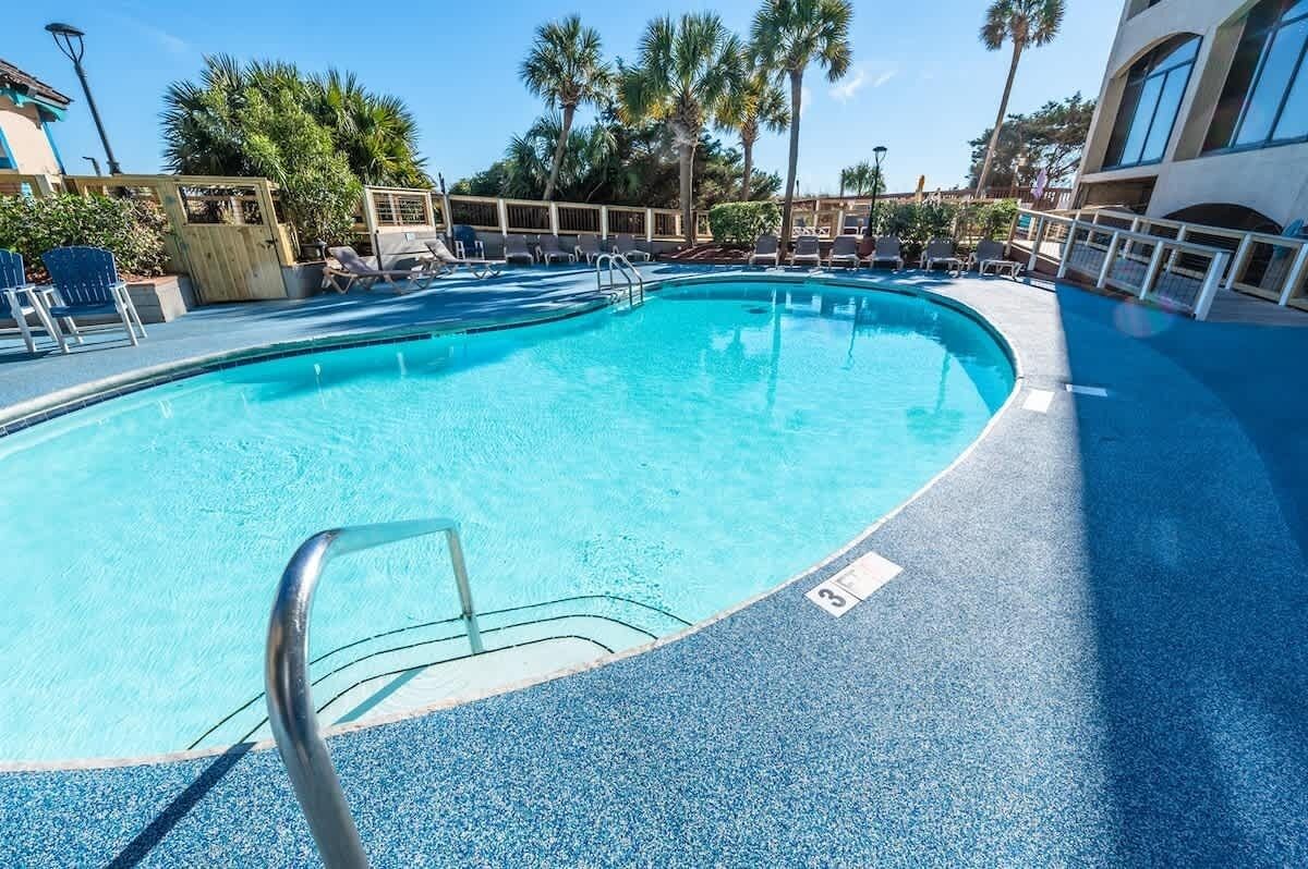 A pool area with lounge chairs and palm trees.