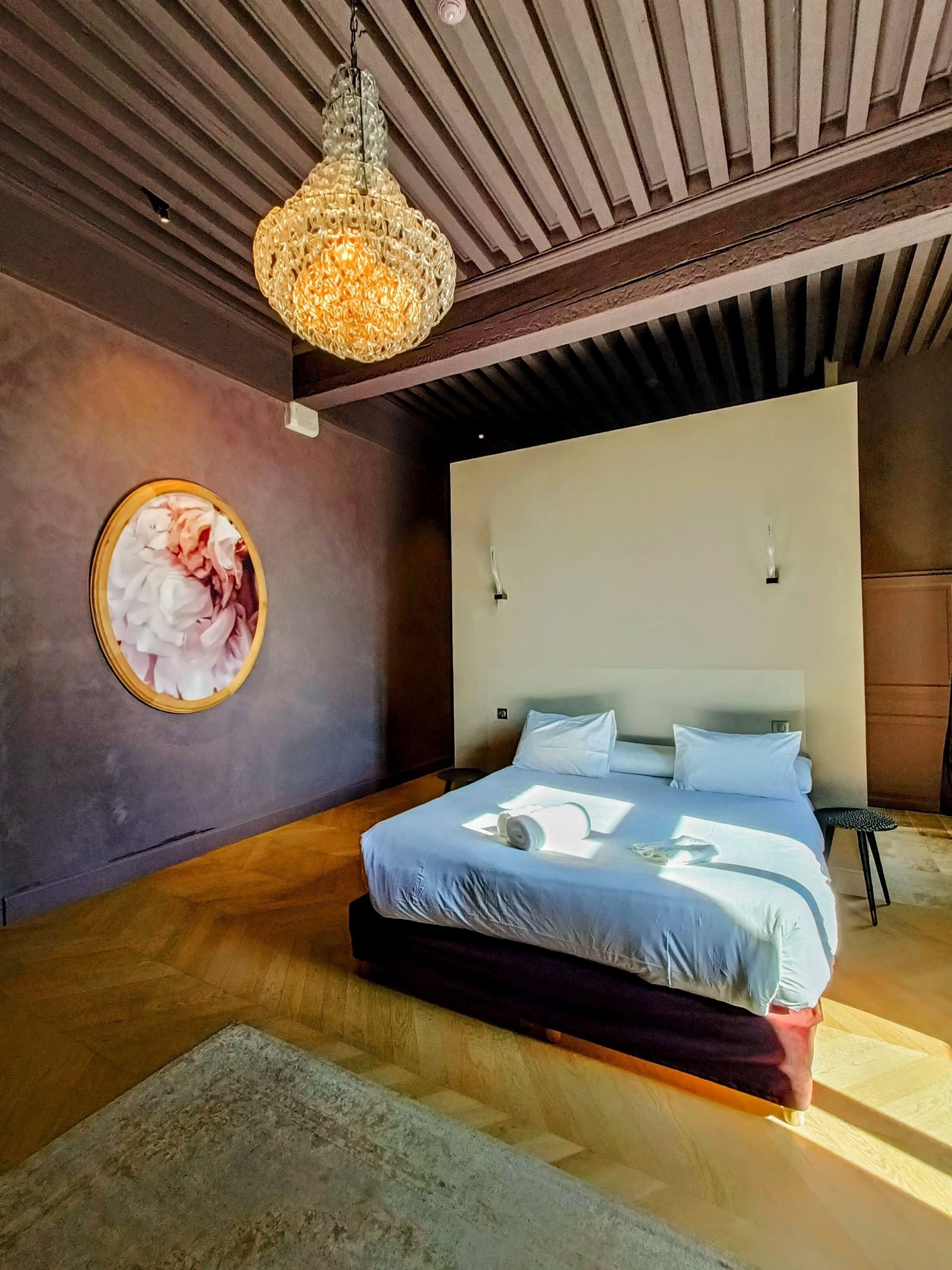 Un dormitorio moderno con una cama grande, una lámpara colgante y una obra enmarcada en la pared.