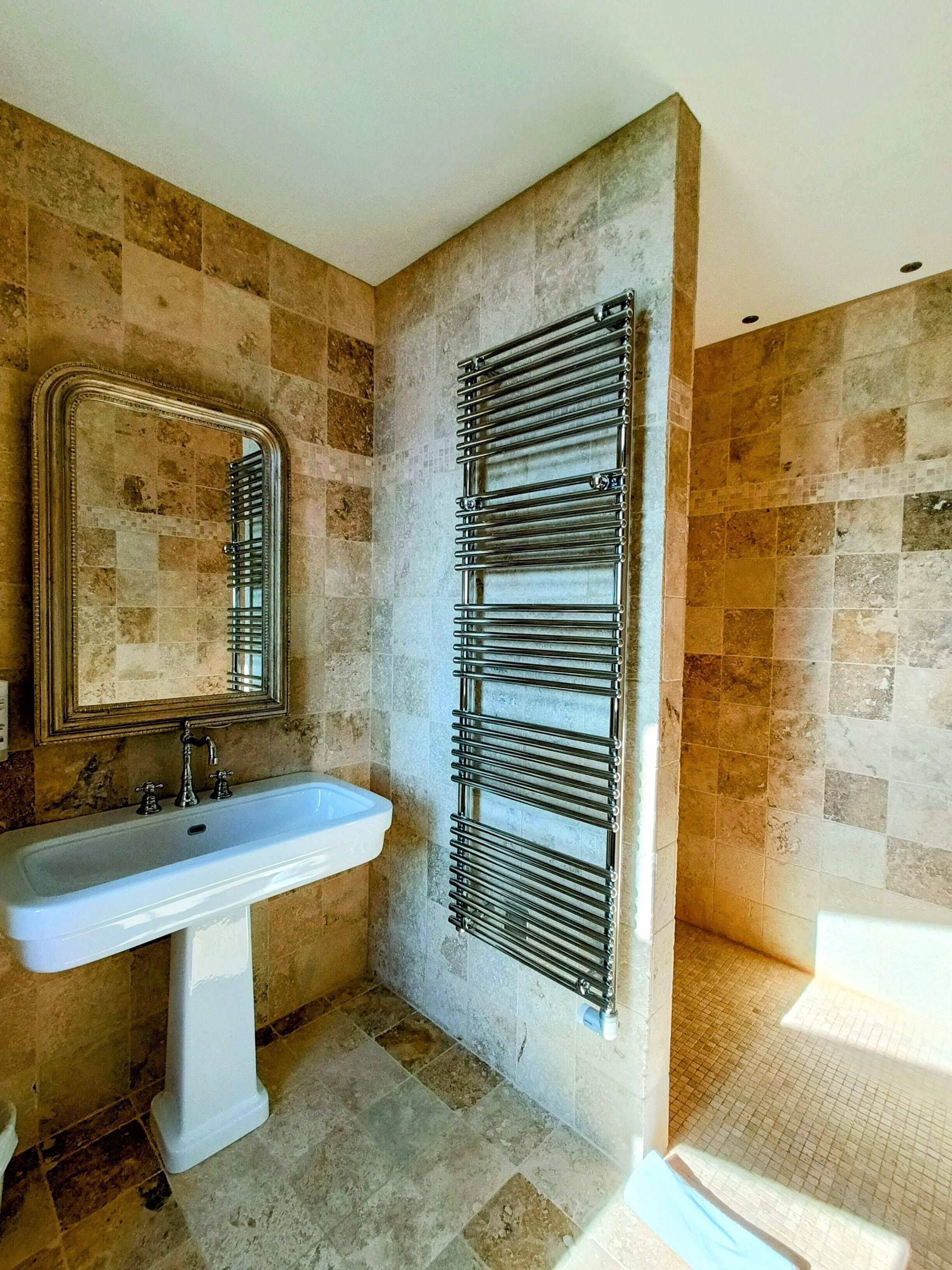 A bathroom with a pedestal sink, a mirror, and a towel rack.