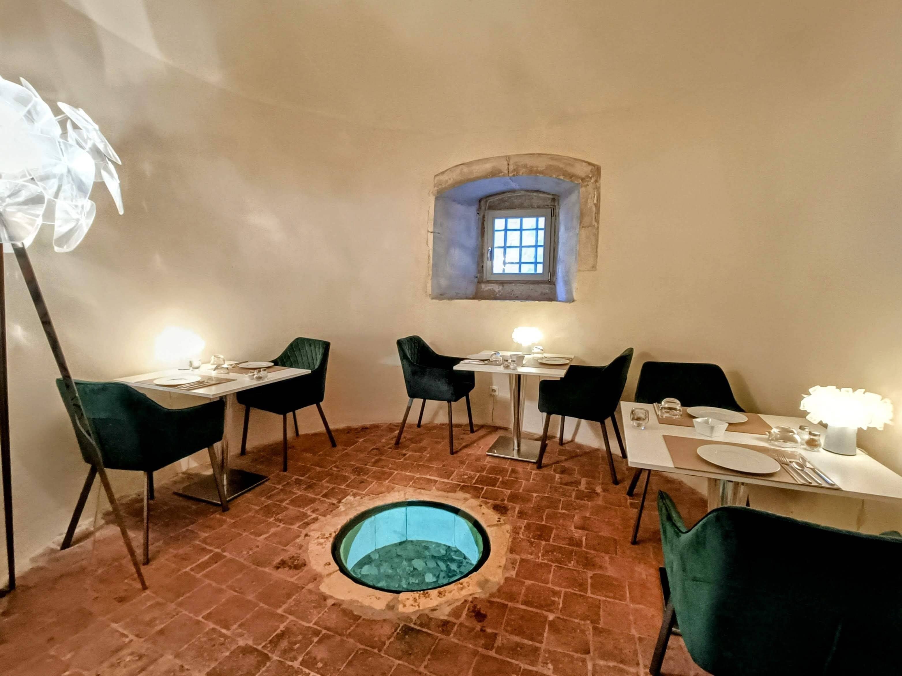 A dining area with brick flooring, a small window, and a circular skylight.