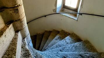 A spiral staircase with a small window at the top, leading to a higher floor.